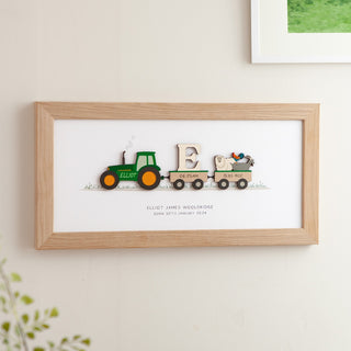 A Personalised Print in a oak frame for a new baby featuring a tractor and trailers with the baby's name and date of birth.
